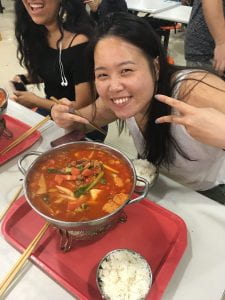 girl posing with a big bowl of soup and a bowl of rice