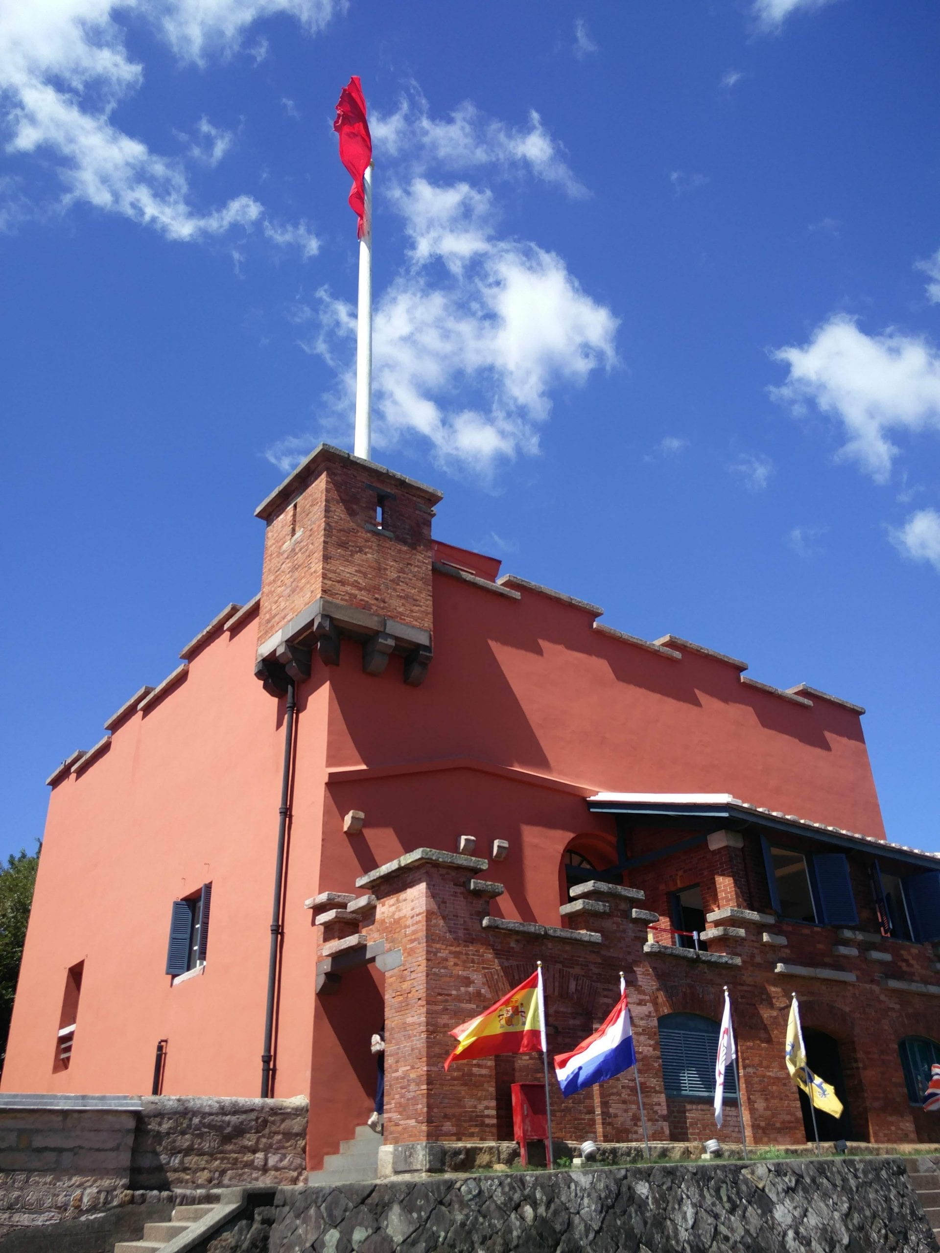 front view of Fort San Domingo with country flags lined up in front and a flag at full staff on the roof