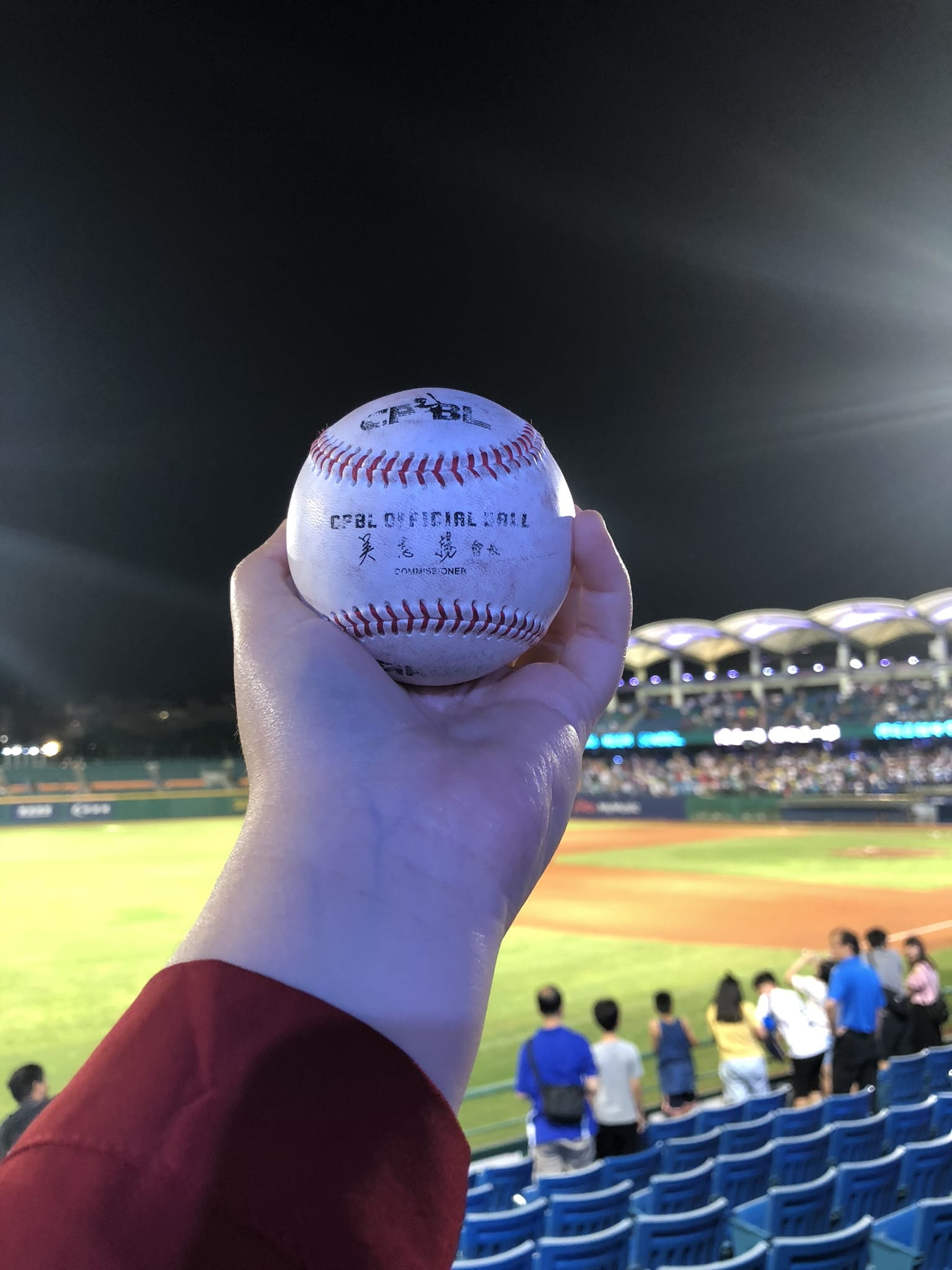 person holding a baseball in their hand overlooking a baseball stadium