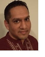 Headshot of Neilesh Bose in brown shirt