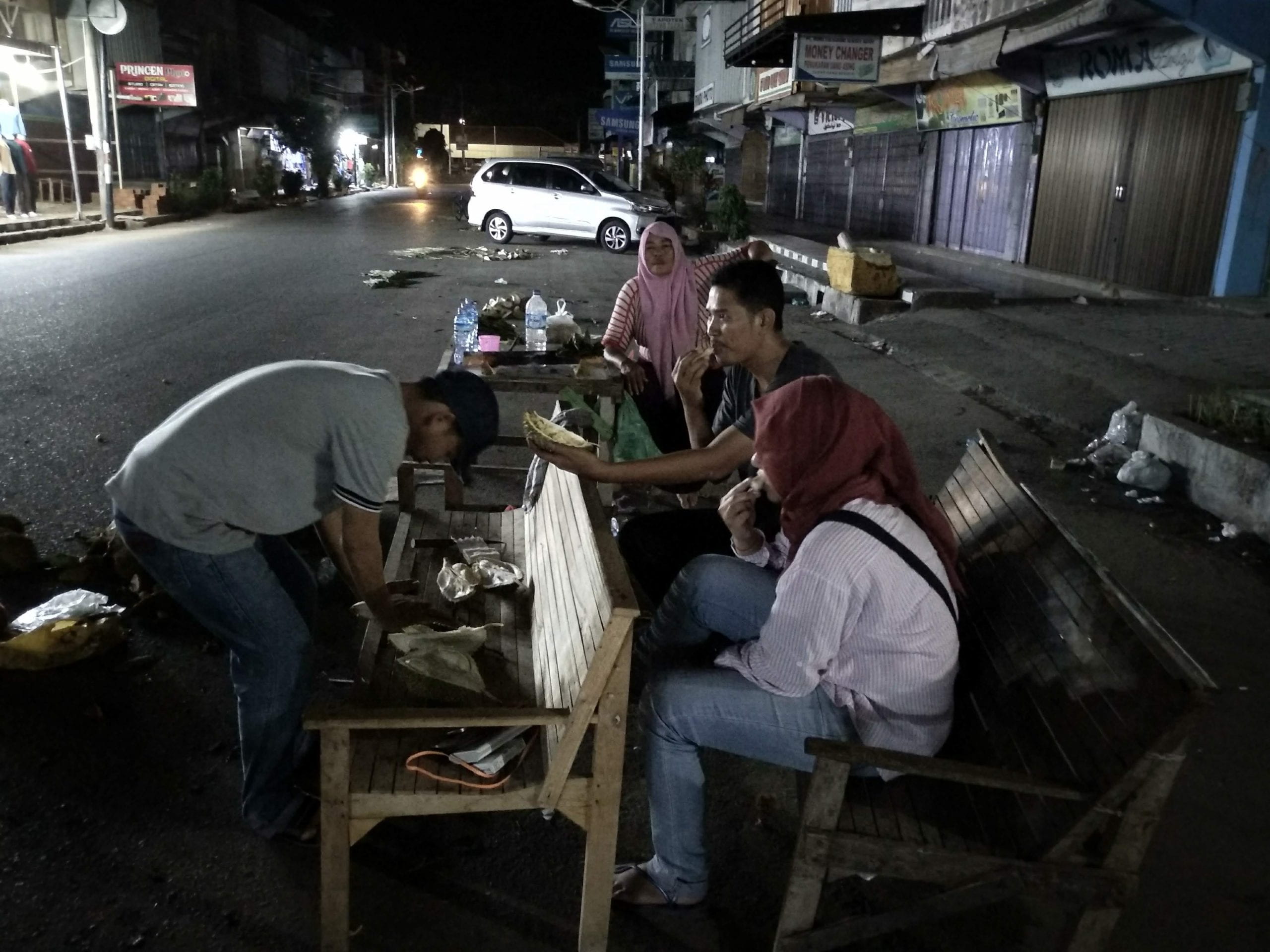 people eating durians outdoors at night in indonesia