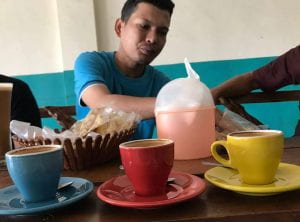 man shares coffee and snacks while discussing Aceh's humanitarianism