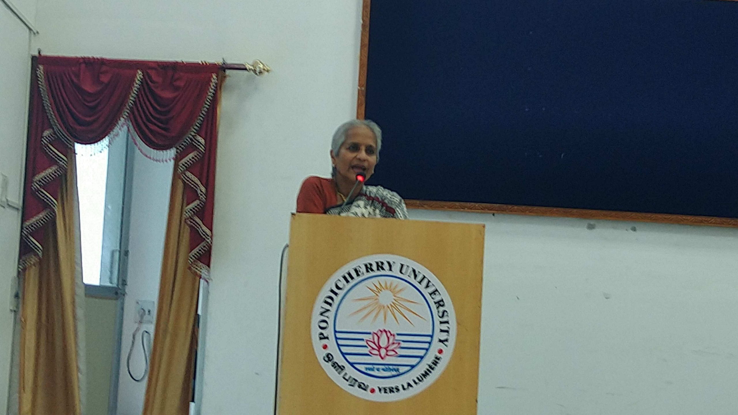 Deepa Ollapally lecturing at Pondicherry University standing at a podium