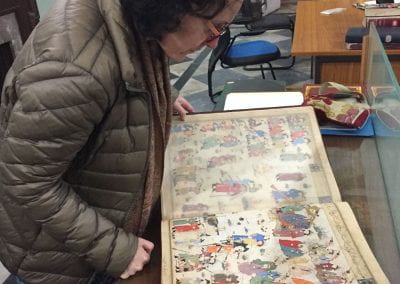 Mika Natif looking at an illustrated manuscript of the World History