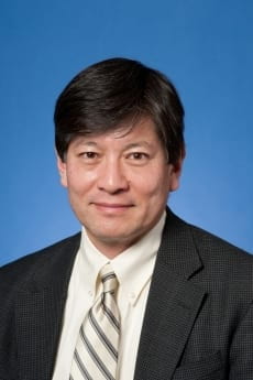 Mike Mochizuki, in professional attire against blue background