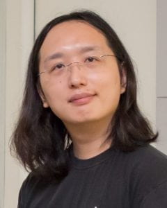 Headshot of Audrey Tang in black shirt and white background