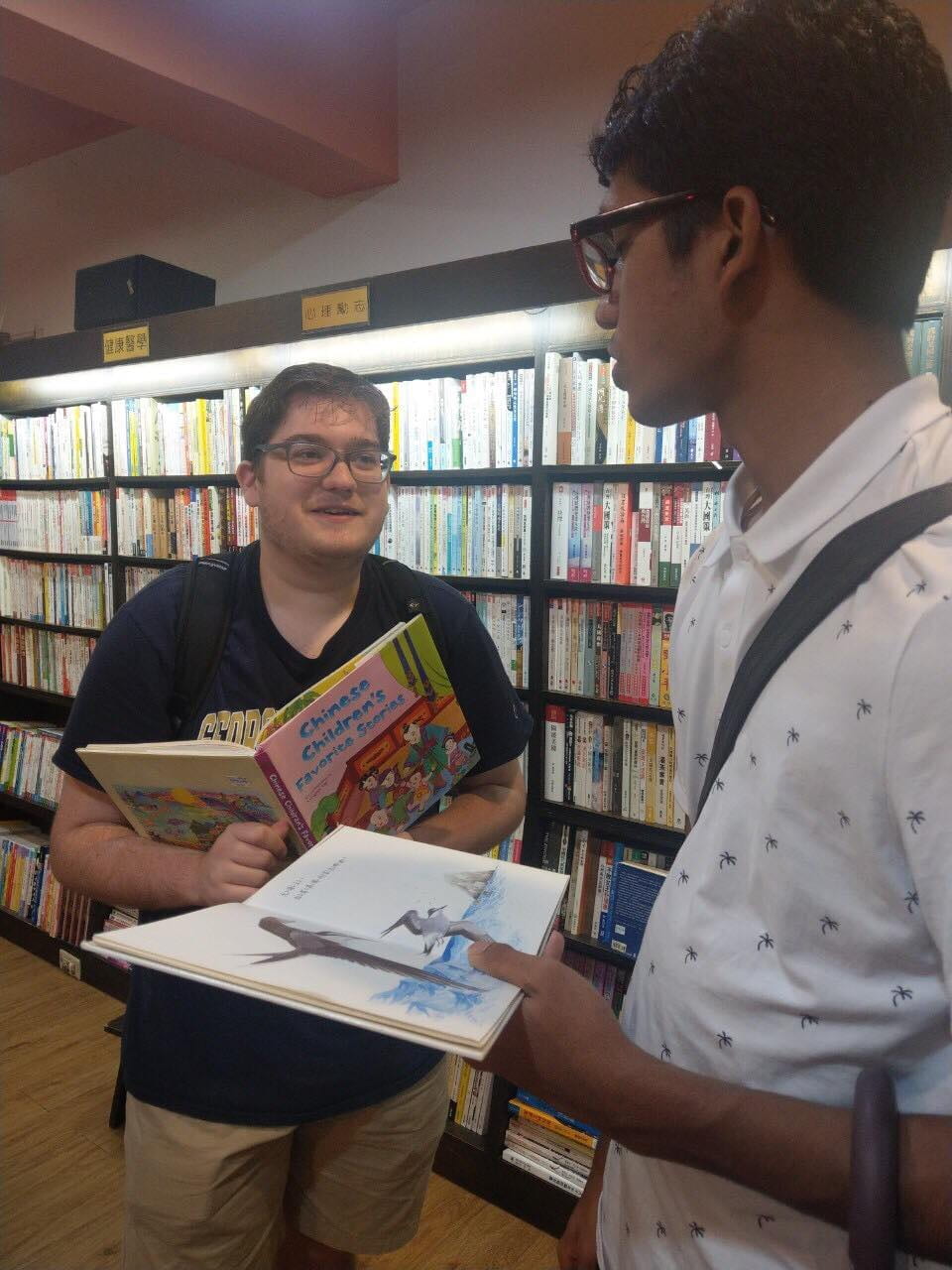 Two Sigur language fellows stand next to each other while holding books in a bookstore