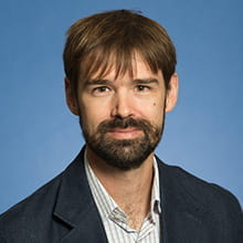Headshot of Ben Hopkins with blue background