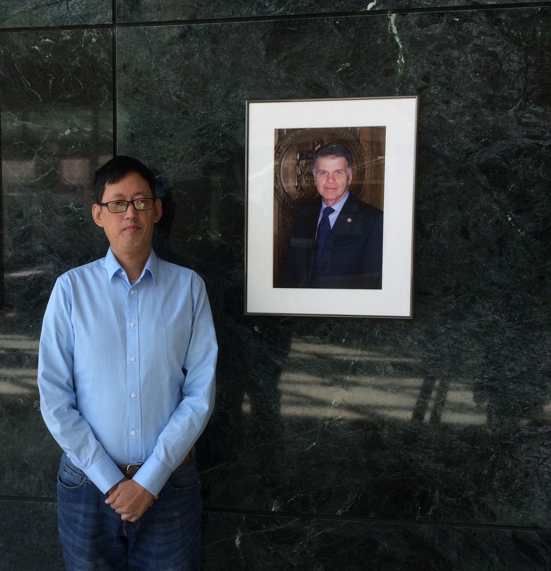Bo Chen pictured with a photograph in professional attire
