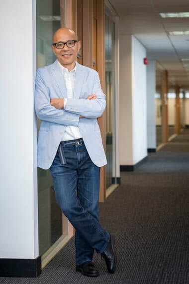 Edwin Lai posing for photo leaning on a wall with arms crossed